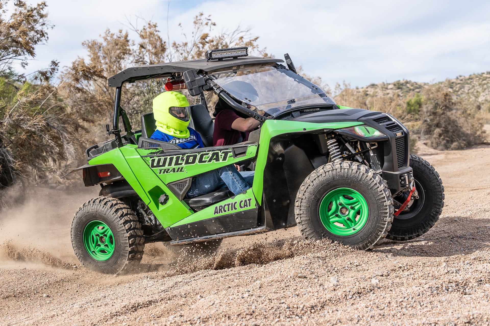 Two men in wildcat arctic cat ATV side by side wearing Headwind helmet cover to protect from dust off road