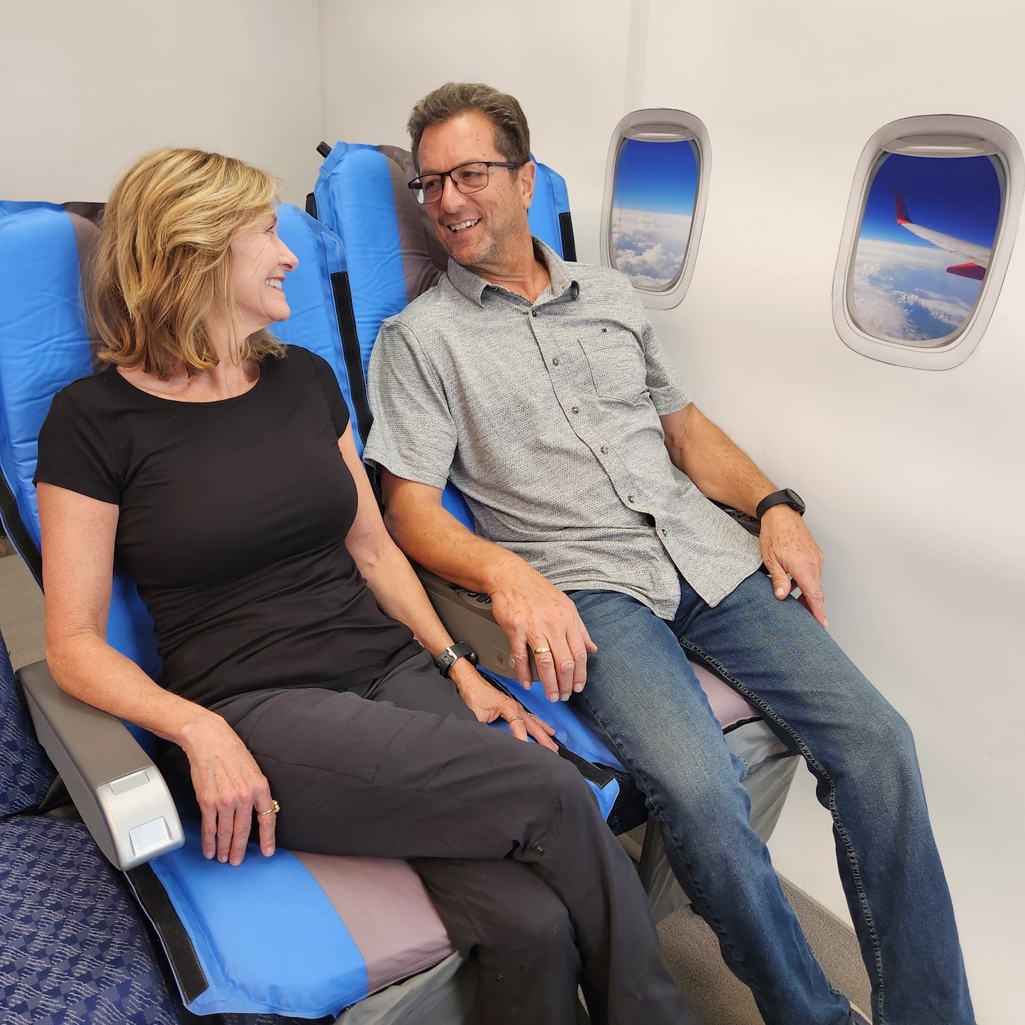Couple sitting on Jet Seat travel self-inflating cushion preventing jet lag