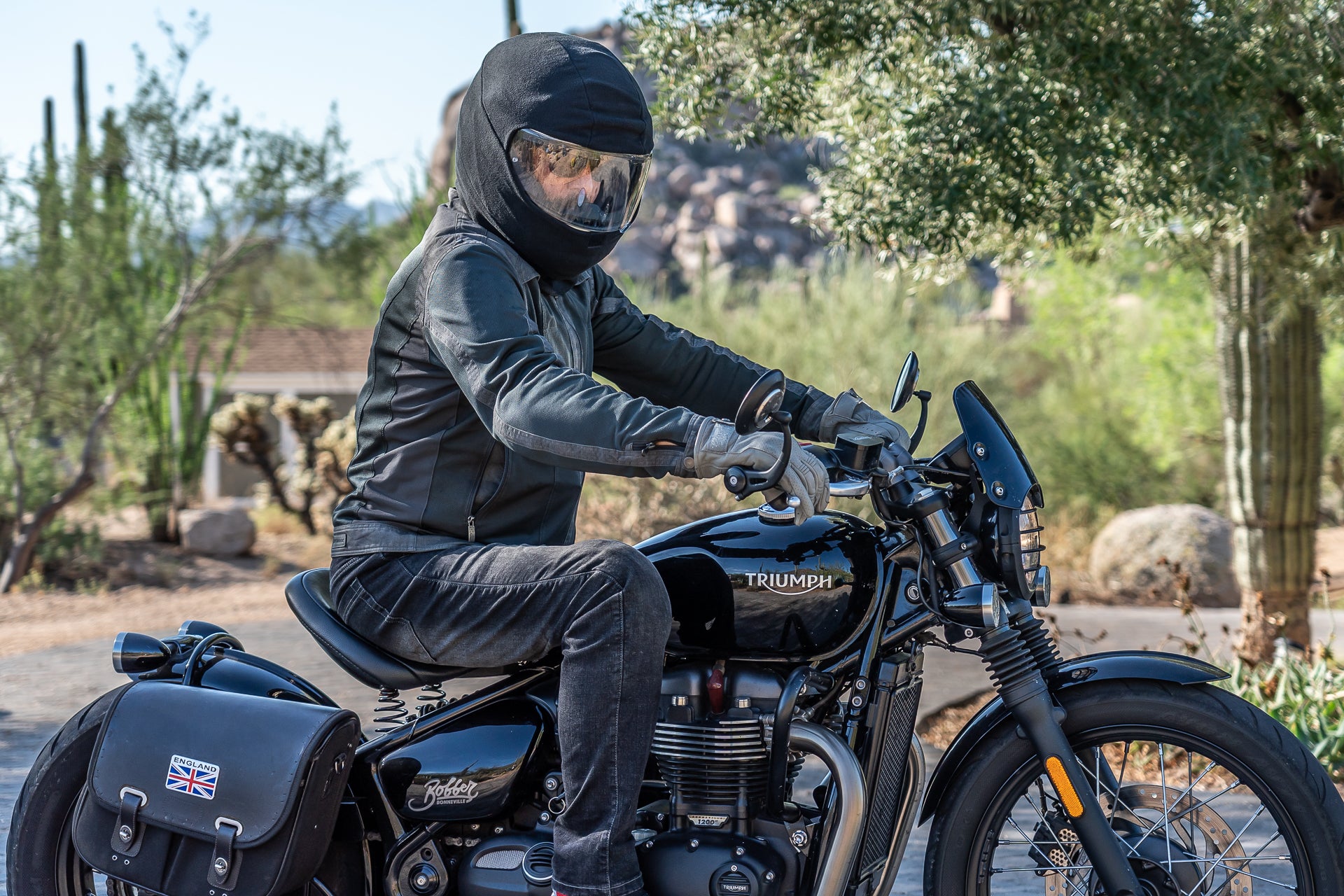Man wearing black fleece breathable helmet cover on Triumph motorcycle 